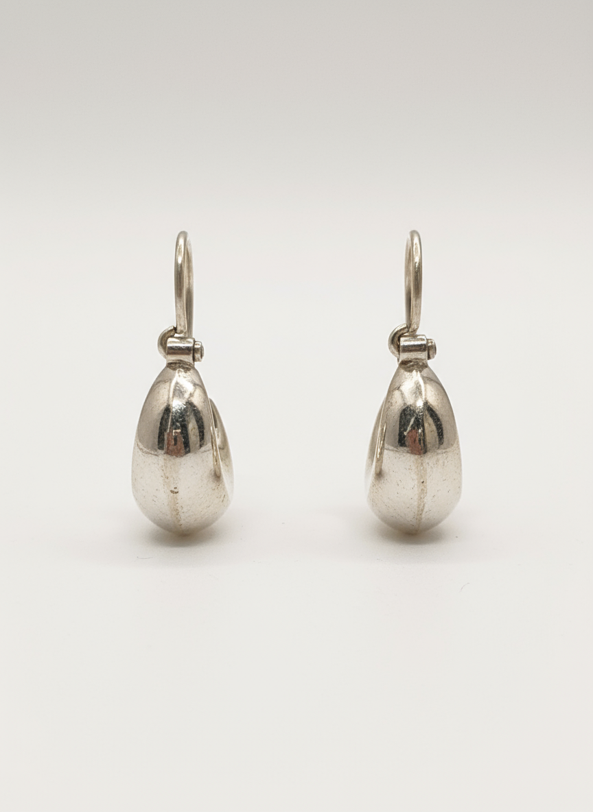 A pair of polished sterling silver teardrop hoop earrings, shown from the front against a white background
