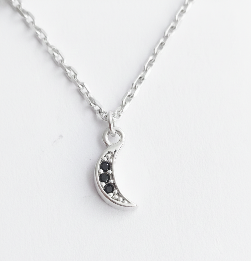 Sterling silver celestial bracelet featuring a star charm, crescent moon with dark stones, and a sparkling crystal